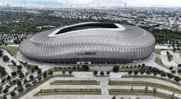 Monterrey — Estadio BBVA: aerial view of a modern stadium with a curved silver roof and mountains nearby.