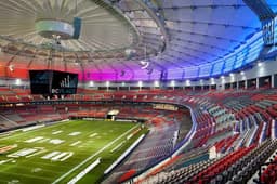 Vancouver — BC Place: aerial view of a stadium with a domed retractable roof lit in purple and red.