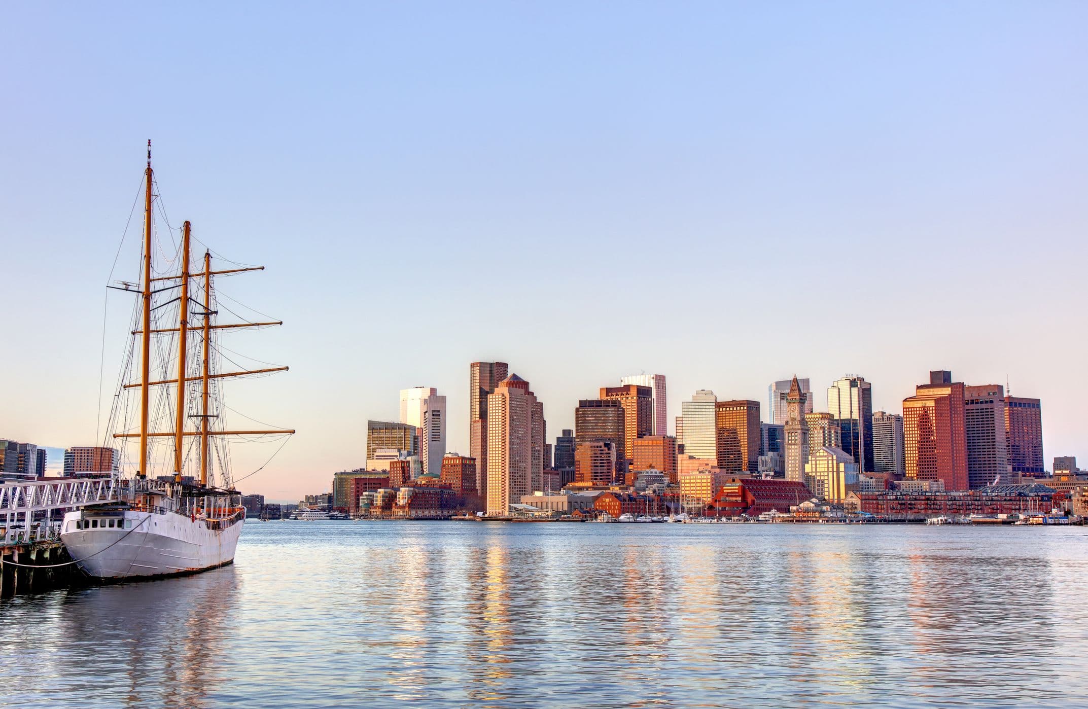 View of Boston skyline from the harbor with a ship/boat in the foreground. 
