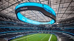 Los Angeles — SoFi Stadium: interior view of a domed stadium with a translucent roof and blue-lit canopy over the field.