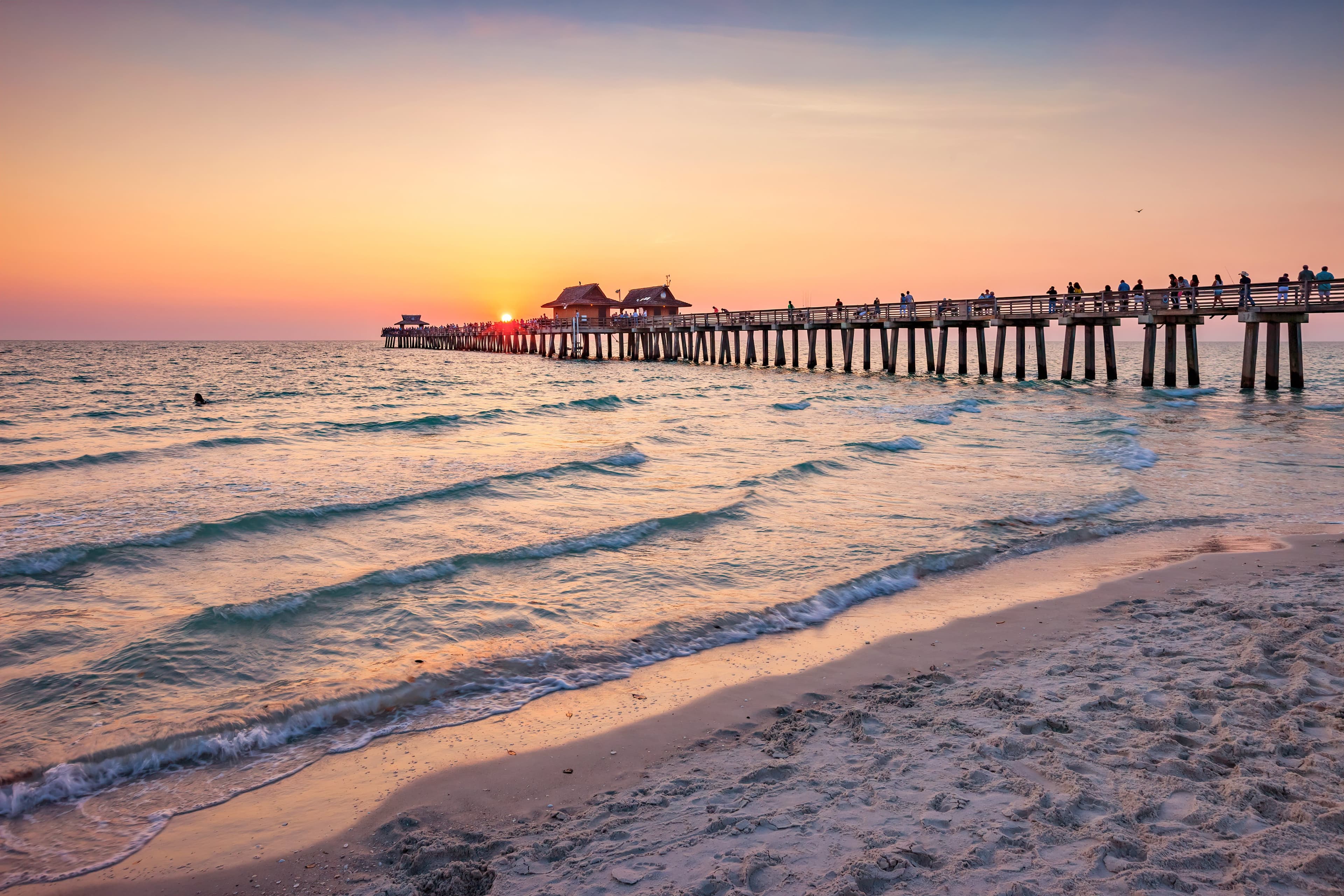 aples Pier at sunset with golden skies and calm Gulf waters along the Florida coastline