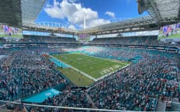 Miami — Hard Rock Stadium: open stadium filled with spectators, green field with end zone markings visible.