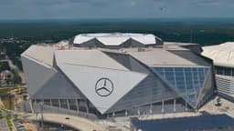 Atlanta — Mercedes-Benz Stadium: aerial view of a stadium with a distinctive angular silver roof.
